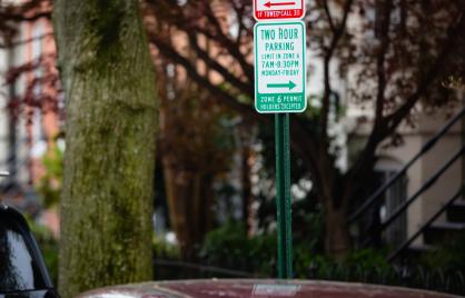 white parking sign with green text on residential DC street