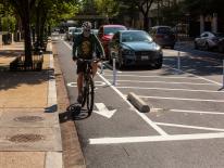 Cyclist riding alongside parked cars in a protected bike lane