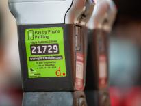 gray double-headed standard parking meter with green park mobile sticker