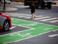 Pedestrian crossing street in crosswalk passing bike symbols