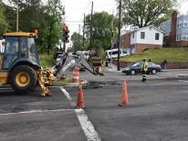 a street repair crew working in an intersection with traffic cones and equipment